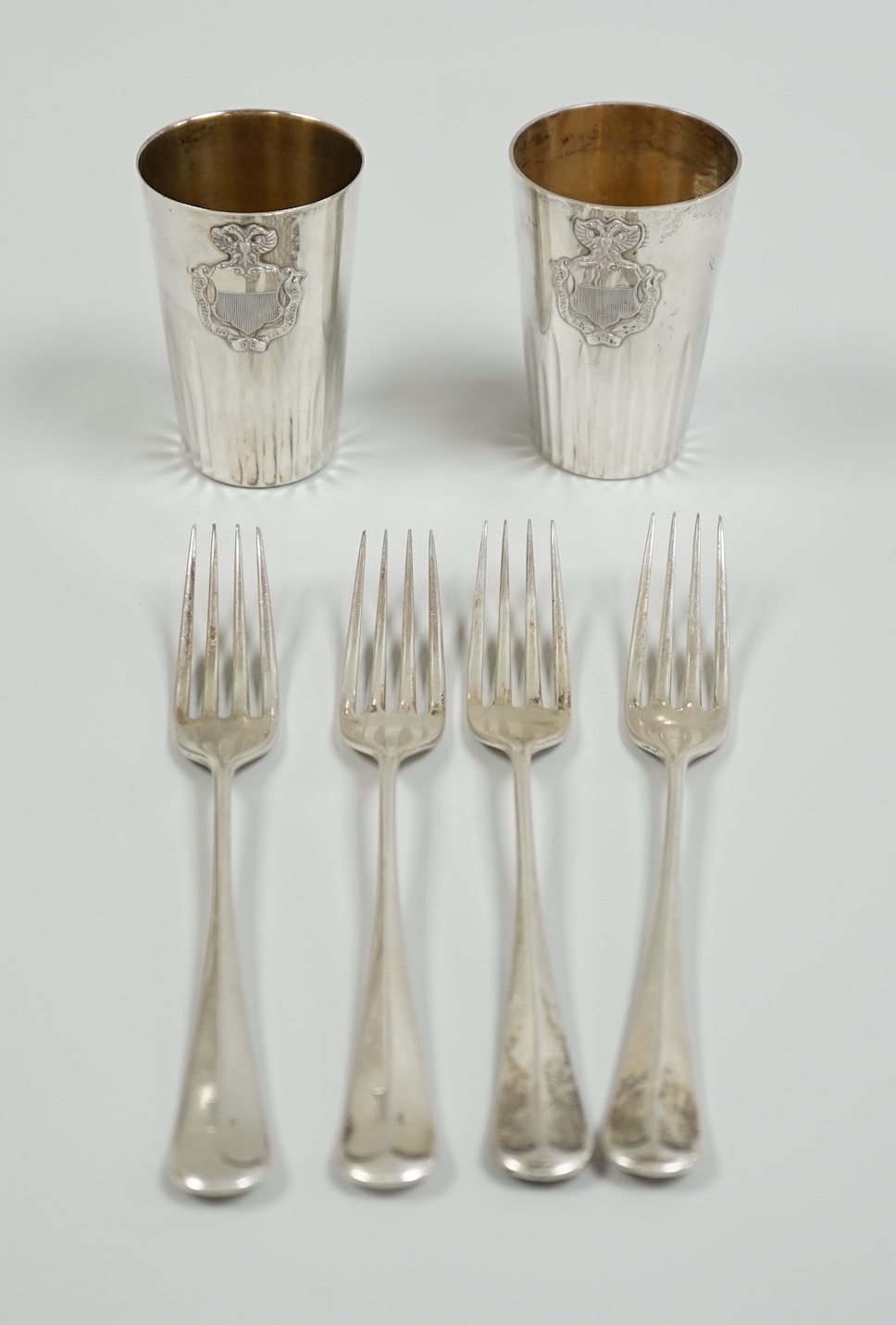 A pair of continental 800 standard white metal beakers, 75mm and four silver rat tail pattern dessert forks, Sheffield, 1929, gross weight 10.3oz.